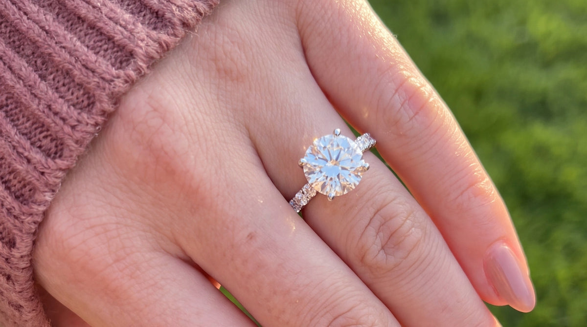 Woman's hand wearing a Moissa moissanite ring, golden hour