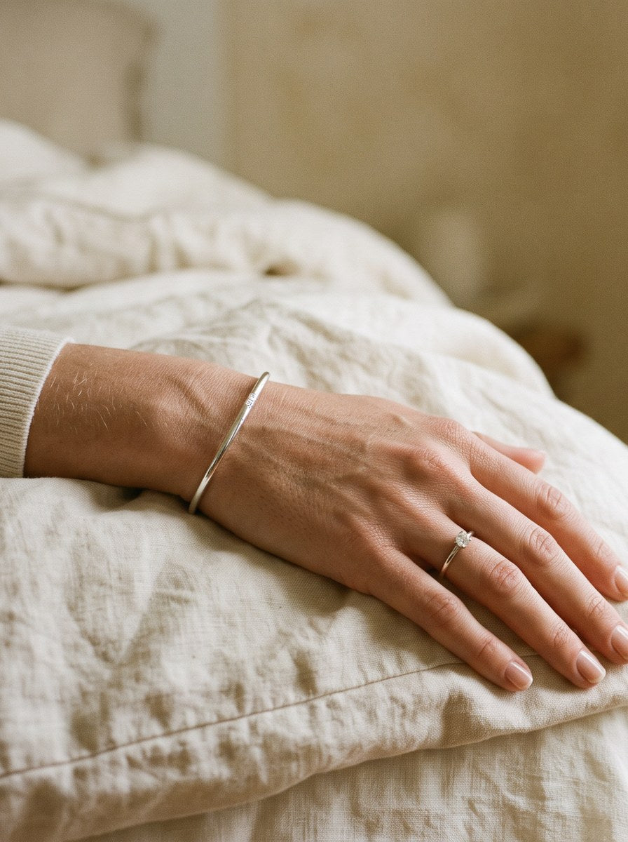 A hand resting on cream linen wearing a silver moissanite solitaire ring